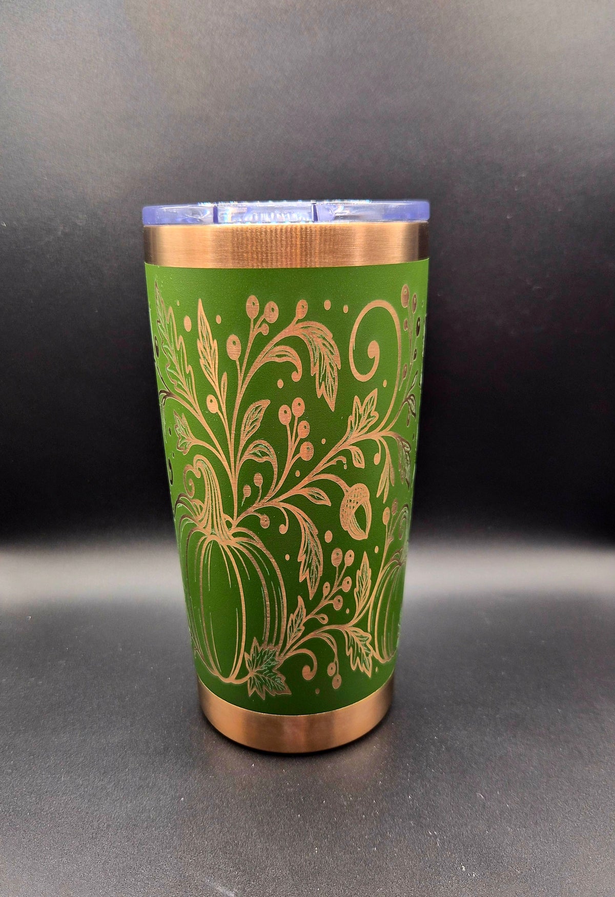 Side view of a green and copper 20 oz laser-engraved fall tumbler featuring detailed pumpkins, autumn leaves, acorns, and decorative botanical scrollwork.