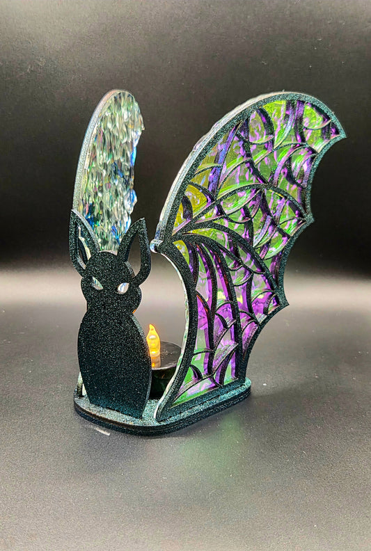 Handcrafted Halloween bat LED tealight holder with black bat silhouette, purple and green iridescent acrylic wings and a glowing tealight.