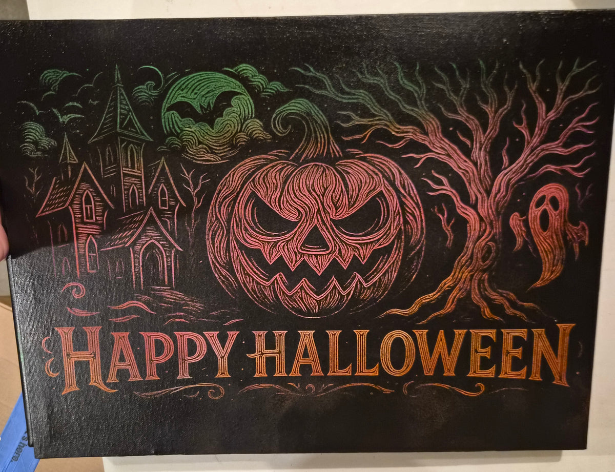 12x18 laser-engraved Halloween canvas wall art featuring an orange jack-o'-lantern, haunted house, twisted tree, ghost and Happy Halloween lettering in vibrant colors against black.
