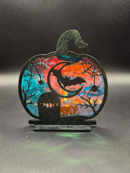 Pumpkin-shaped Halloween tabletop decoration featuring a crescent moon, bat, spiders and SPOOKY gravestone with iridescent backing.
